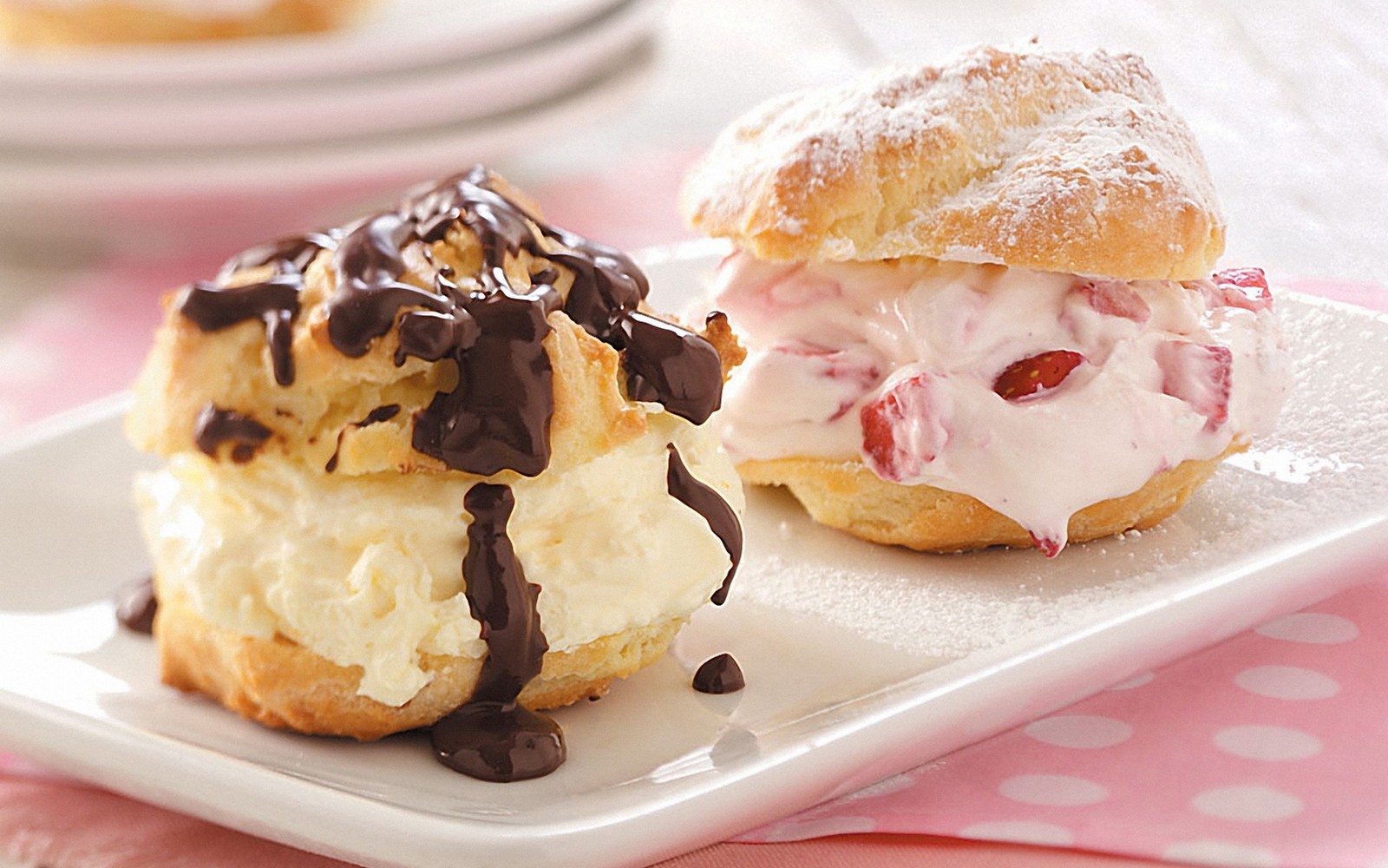 Hay dos pasteles en un plato con salsa de chocolate (profiterole, comida, postre congelado, glaseado, caramelo)