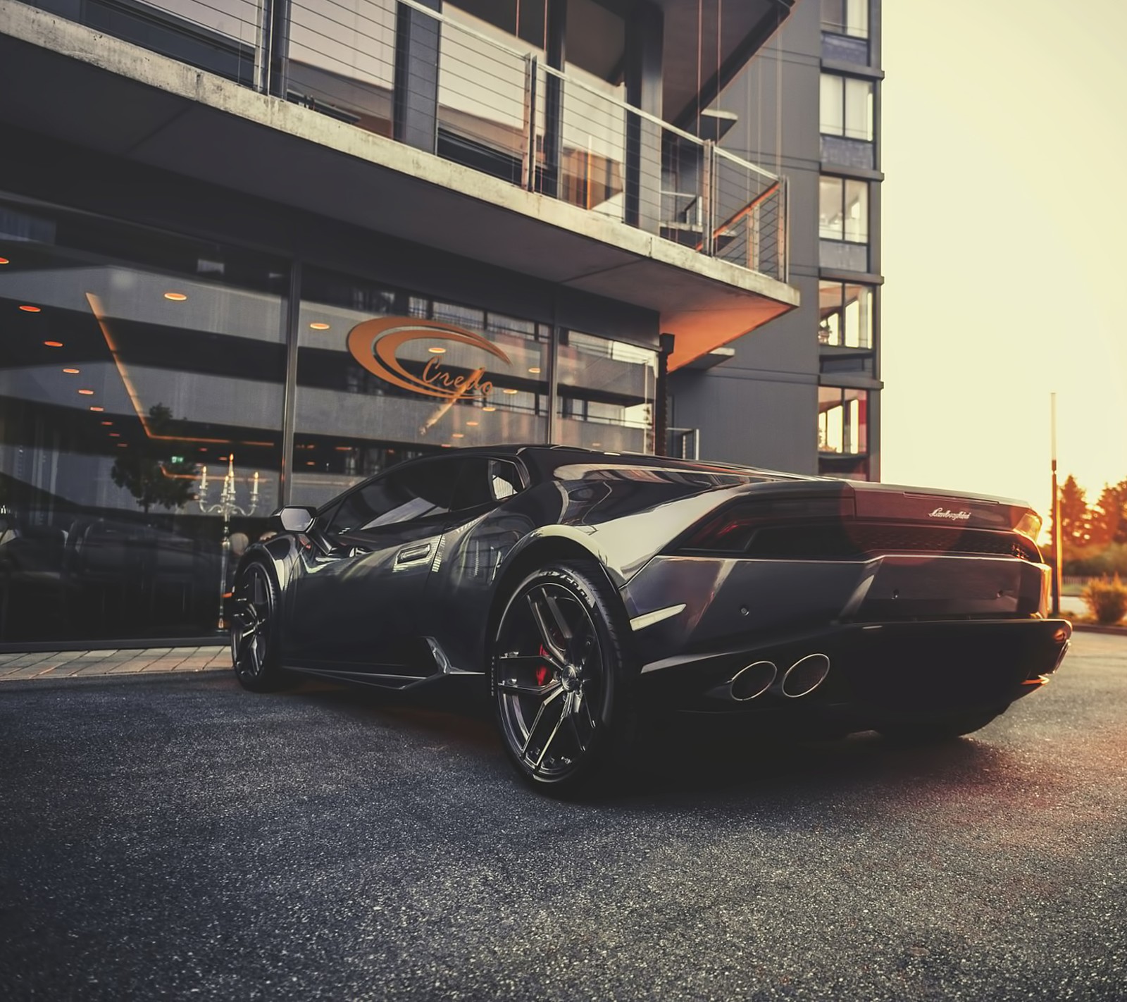 Un gros plan d'une voiture de sport noire garée devant un bâtiment (voiture, lamborghini)