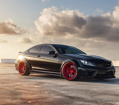 Mercedes C63 AMG Coupe mit auffälligen roten Rädern vor einem dramatischen Himmel.