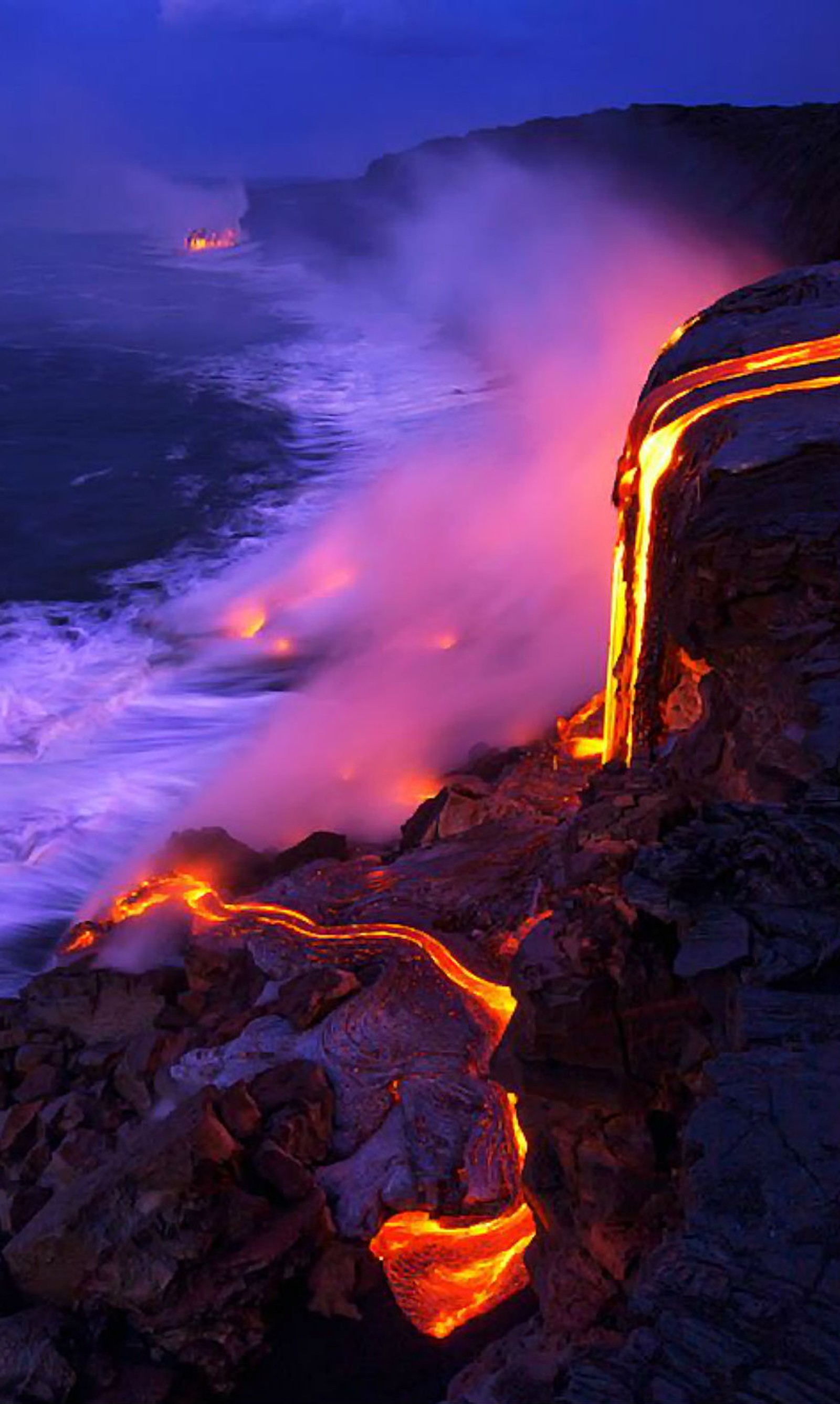 Imagen borrosa de lava fluyendo hacia el océano por la noche con un barco a lo lejos (negro, quemar, mortal, erupción, fuego)