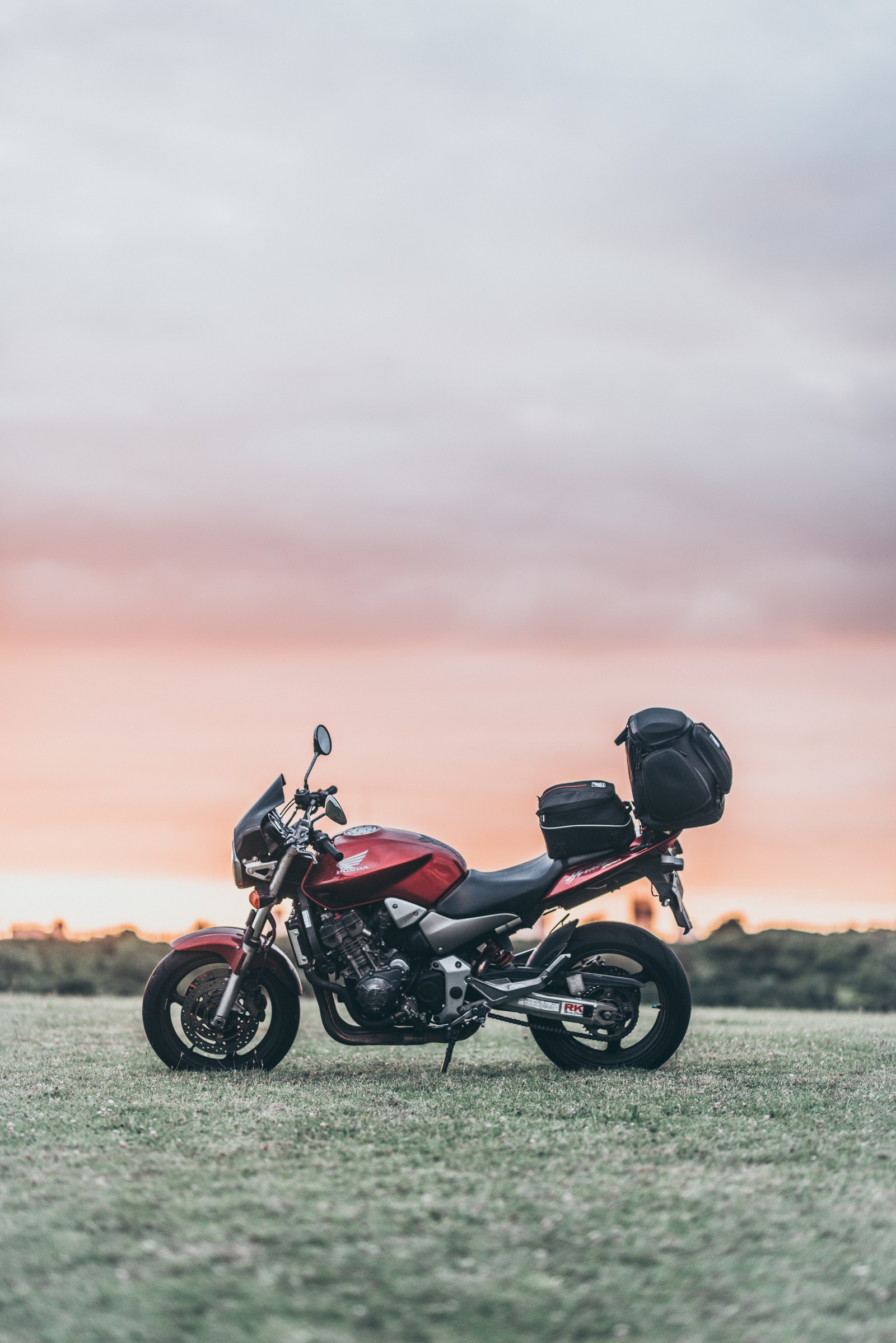 Motocicleta arafed estacionada em um campo com um pôr do sol ao fundo (motocicleta, scooter, motociclismo, verão, nuvem)