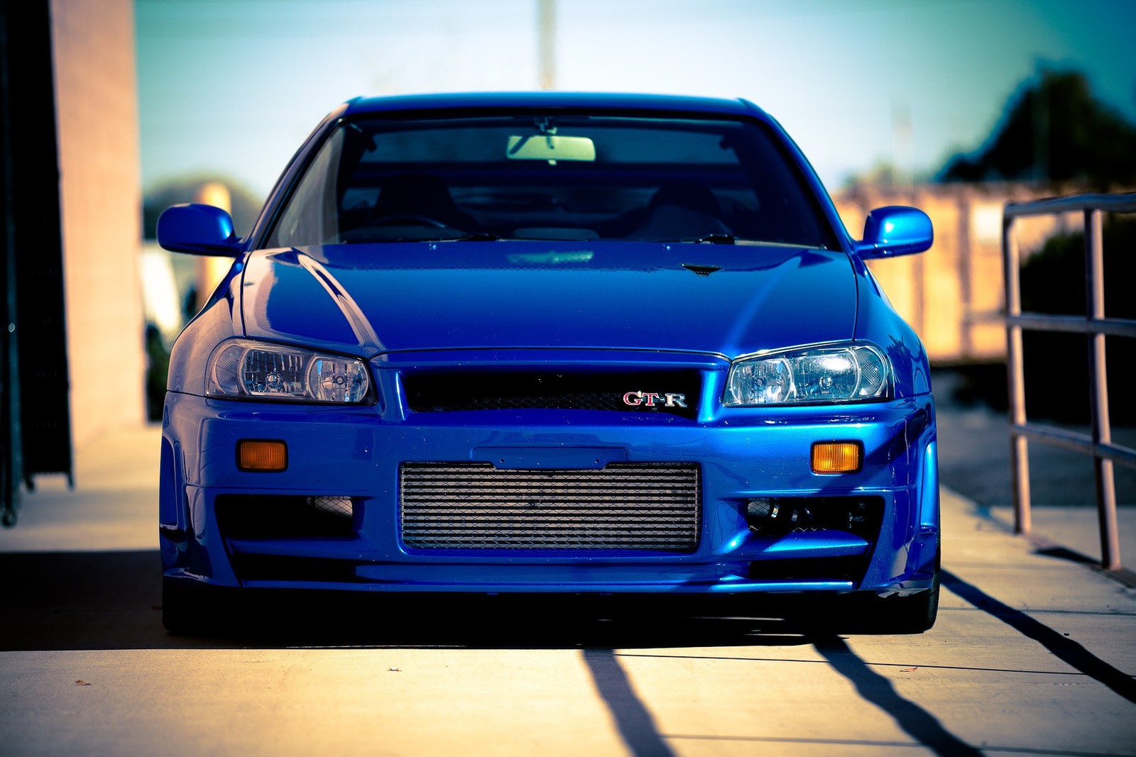 A close up of a blue car parked in a parking lot (nissan, car, automotive lighting, sports car, bumper)