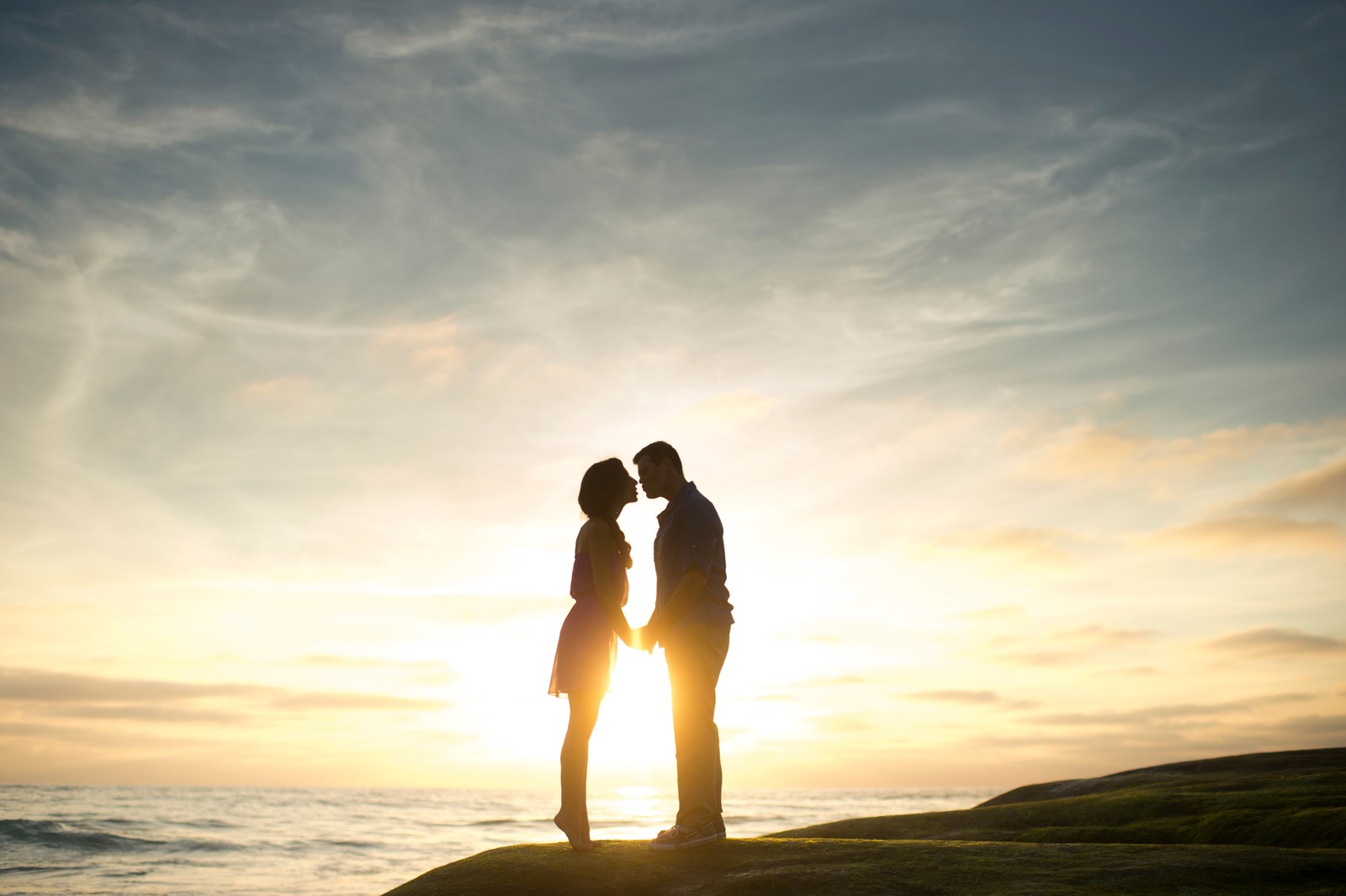 Deux personnes se tiennent sur un rocher avec le soleil qui se couche (romance, personnes dans la nature, amour, horizon, amitié)