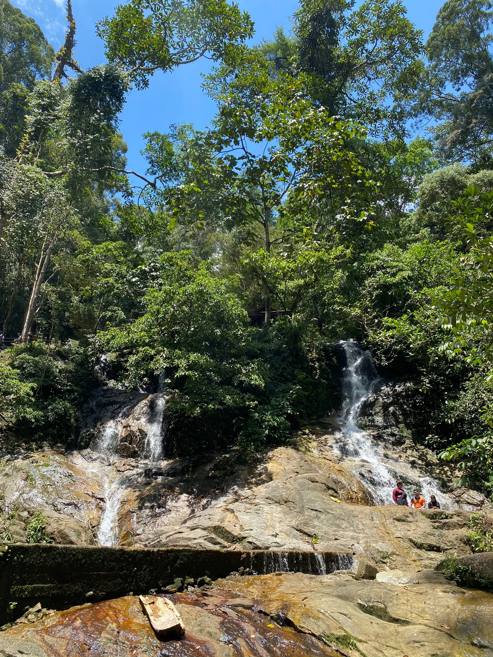 De nombreuses personnes assises sur des rochers près d'une chute d'eau (la cascade, nature, ressources en eau, paysage naturel, ruisseau)