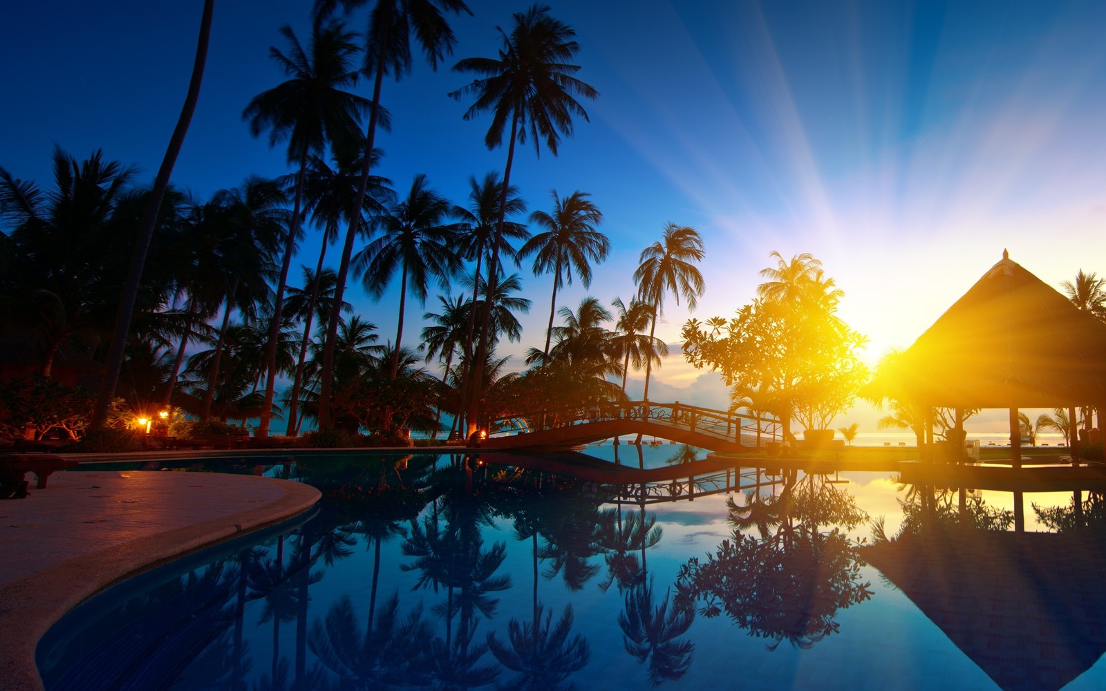 Pôr do sol sobre uma piscina com um gazebo e palmeiras (mar, estância, piscina, trópicos, palmeira)