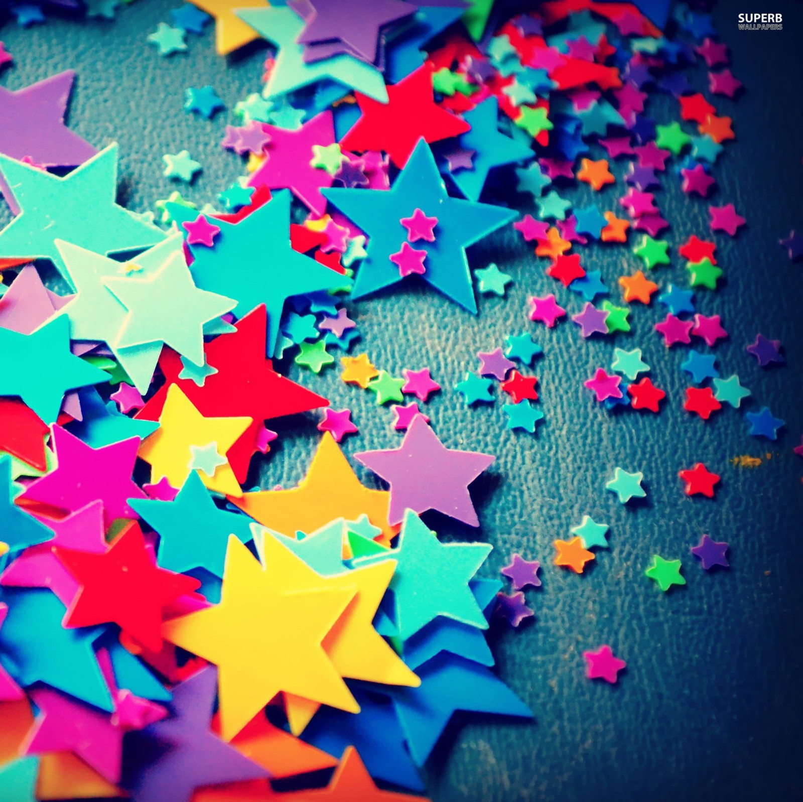 Brightly colored stars scattered on a table with a black background (blue, colorful, green, other, red)