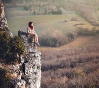 Um momento sereno de reflexão no topo de um penhasco rochoso, capturando a beleza da natureza e da solidão.