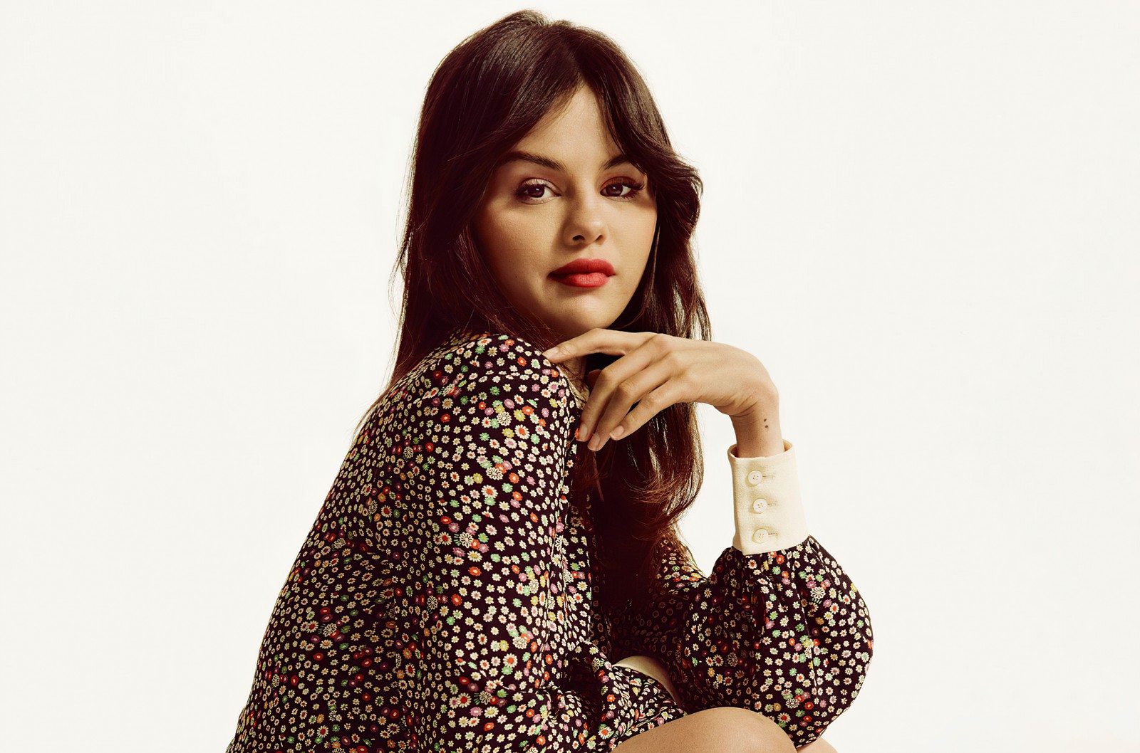 Une femme est assise sur un tabouret avec la main sur le menton (selena gomez, fond blanc, portrait, 5k, gens)