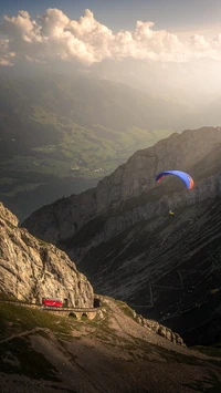 Paraglider Soaring Above Alpine Landscape at Sunset