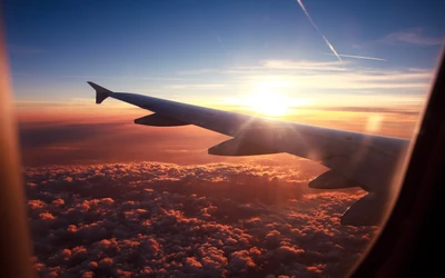 Sonnenuntergang über den Wolken: Luftaufnahme vom Flugzeugflügel