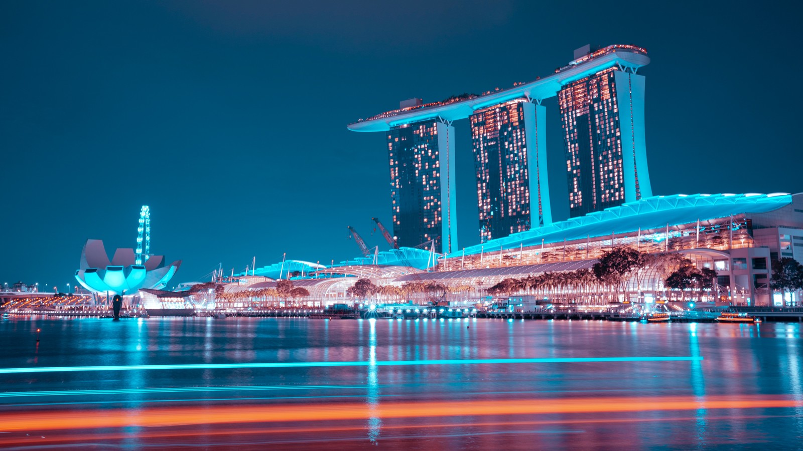 Uma vista do horizonte da cidade à noite com um barco na água (marina bay sands, hotel, singapura, hora azul, luzes noturnas)