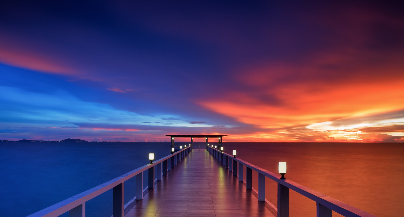 Um longo cais com um banco e luzes nele ao pôr do sol (pier de madeira, 5k, ponte, por do sol, horizonte)