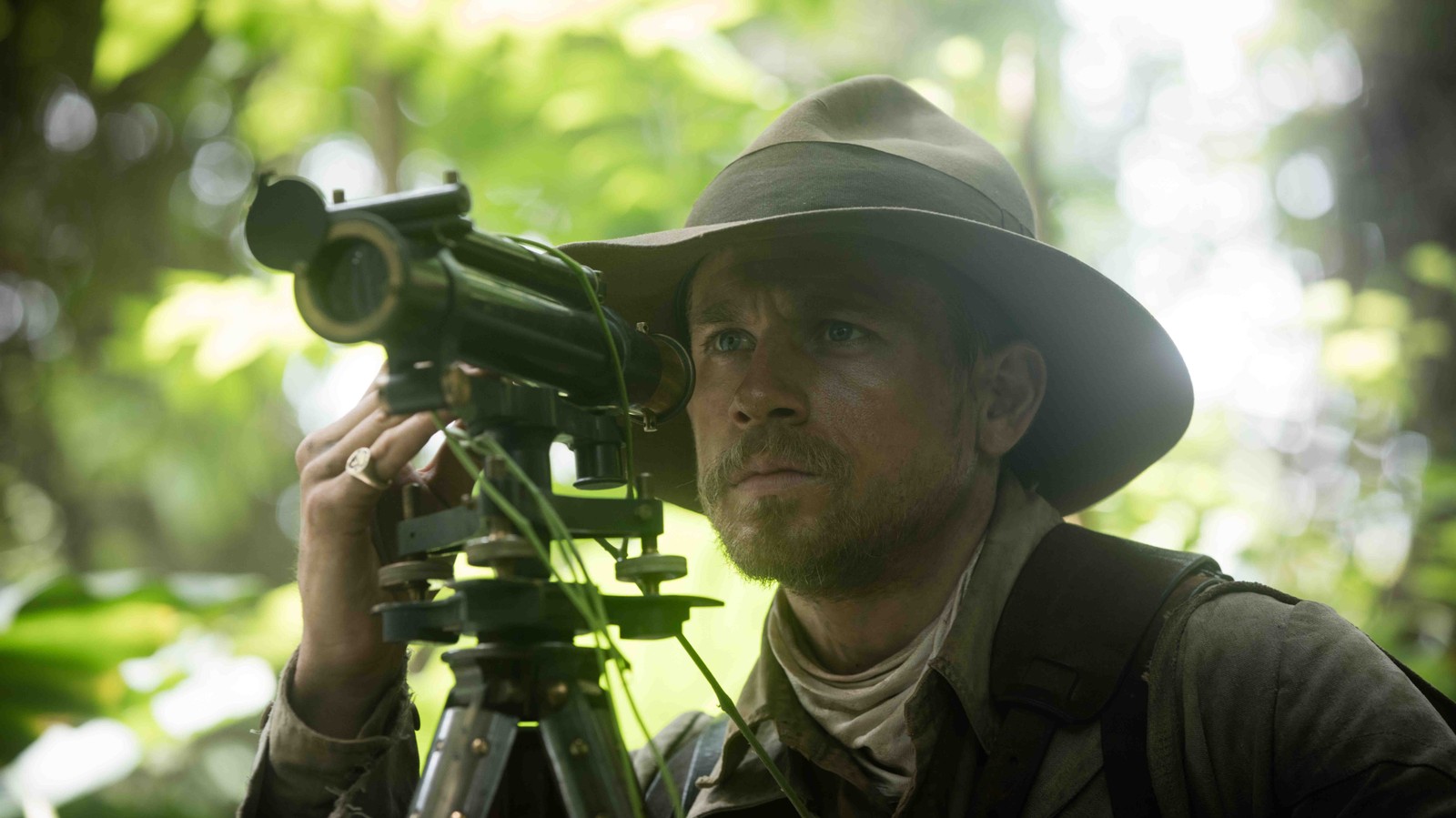 Arafed man in a hat and jacket holding a camera (camera operator, soldier, united kingdom, film, tree)