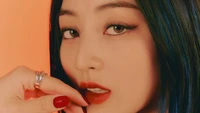 Jihyo de TWICE présentant un gros plan frappant avec un maquillage audacieux sur un fond orange vif.