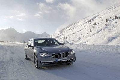 BMW 7 Series cruising on a snowy mountain road.