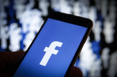 Smartphone exibindo o logotipo do Facebook contra um fundo desfocado de ícones de redes sociais