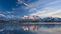 Majestätische Bergkette, die sich in einem ruhigen See unter einem weiten Himmel spiegelt