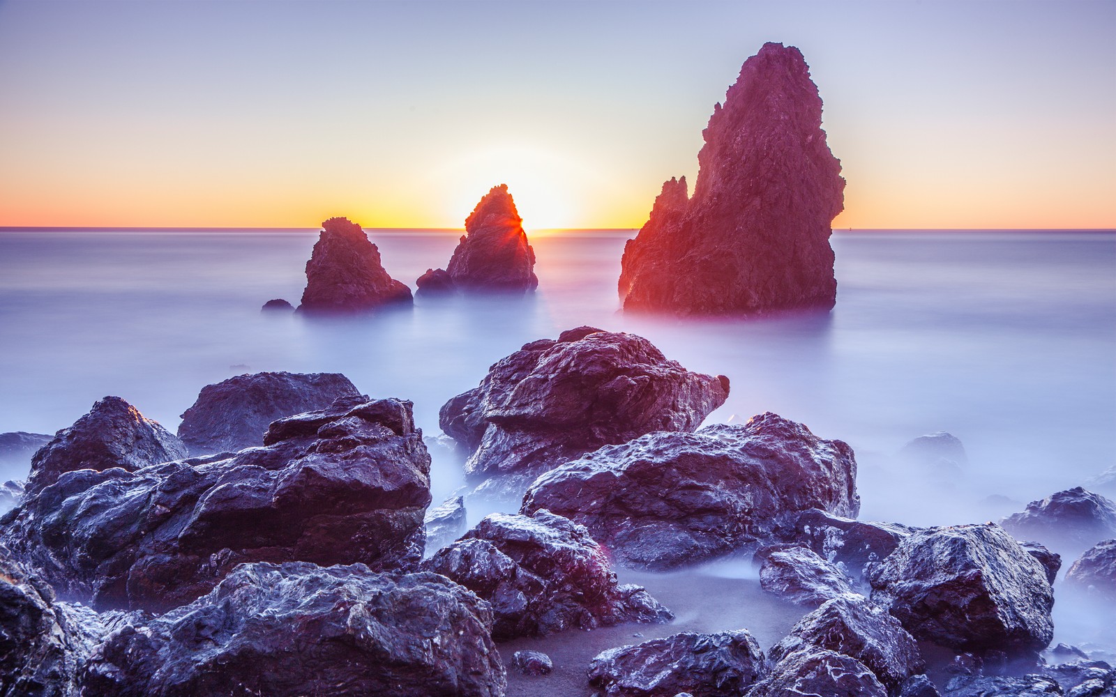 Rochas arafed no oceano ao pôr do sol com um fundo de céu (rodeo beach, marin headlands, califórnia, california, por do sol)