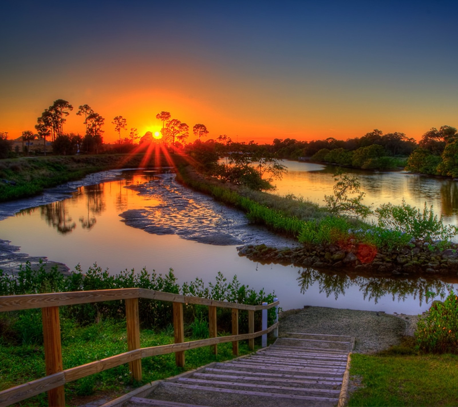 Arafed view of a river with a wooden bridge and a sunset (hd, landscape, nature, sunset)