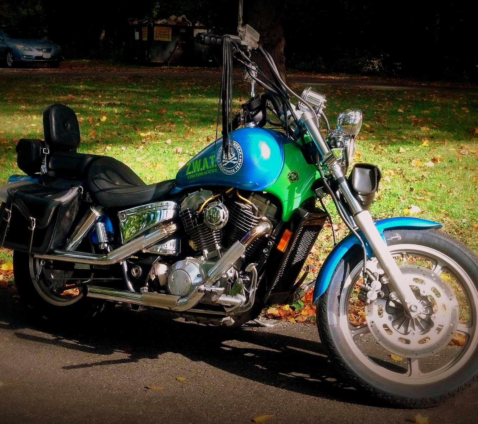 Une moto bleue et verte garée sur le bord de la route (vélo, croiseur, honda, moto, zombie)