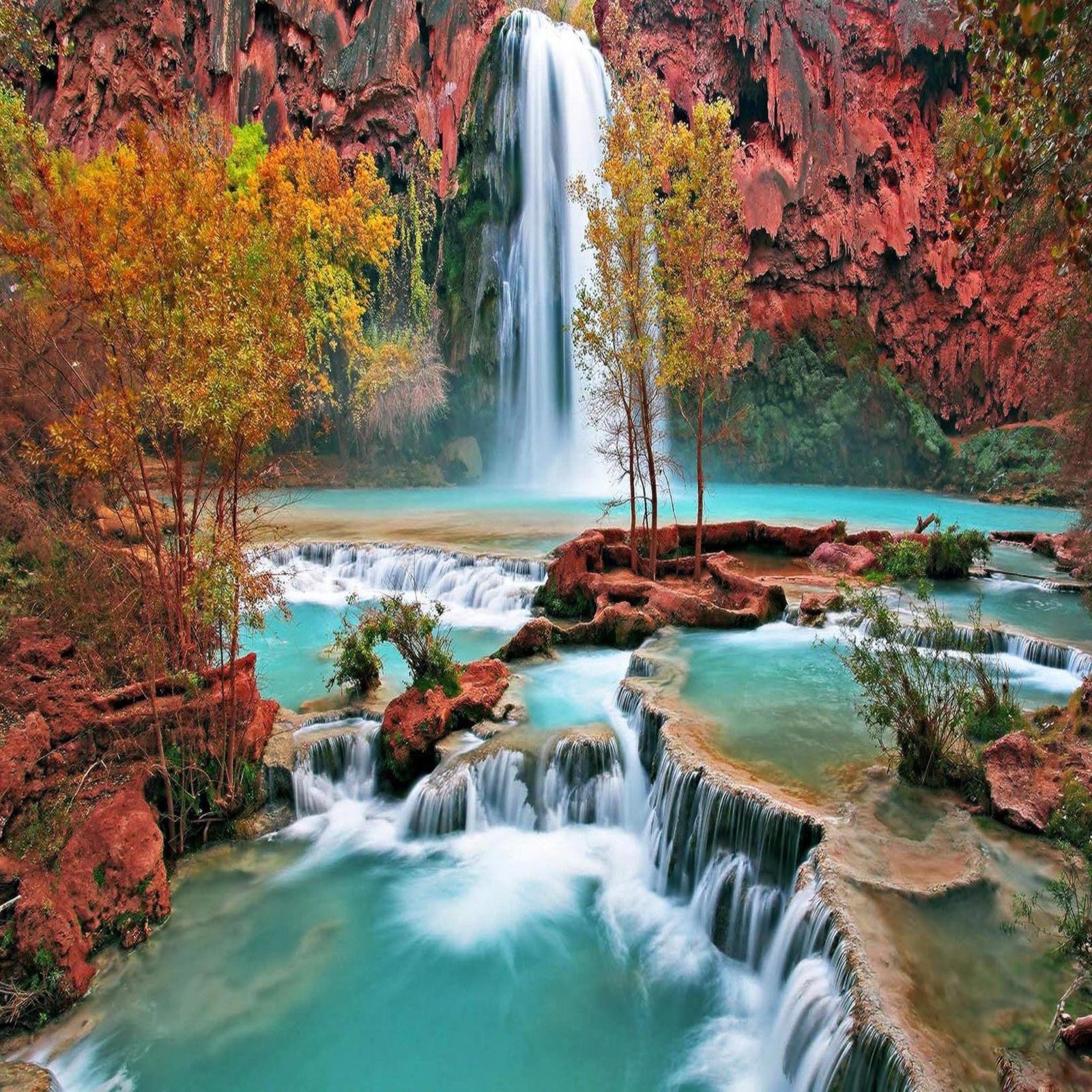 Una gran cascada en medio de un bosque con una piscina azul (hermoso, lindo, mirada, agradable)