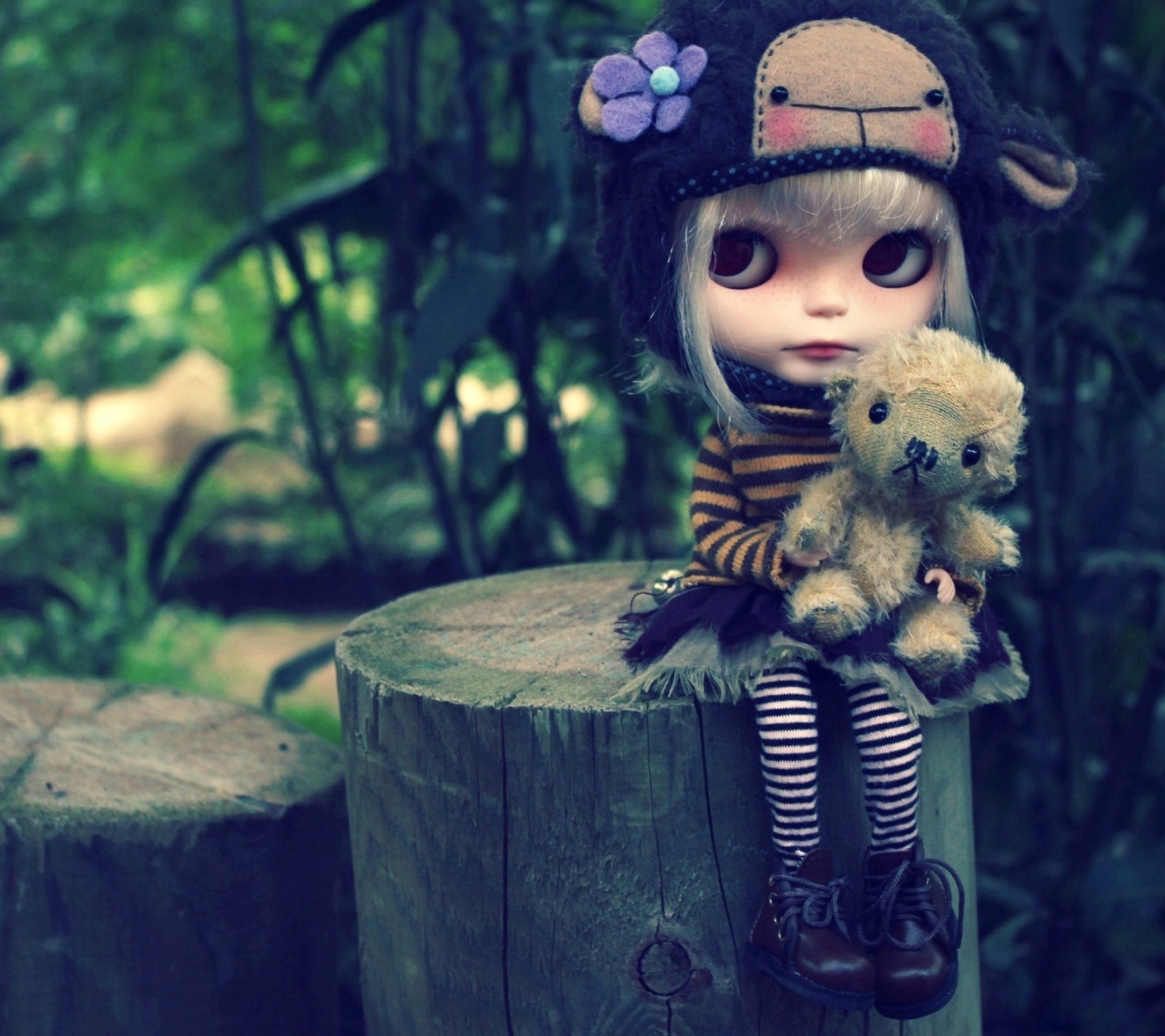 There is a doll sitting on a stump with a teddy bear (awesome, love)