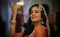 Katrina Kaif rayonne de beauté et de tradition dans une tenue rouge vibrante, ornée de bijoux et d'accessoires complexes, encapsulant l'élégance de Bollywood.