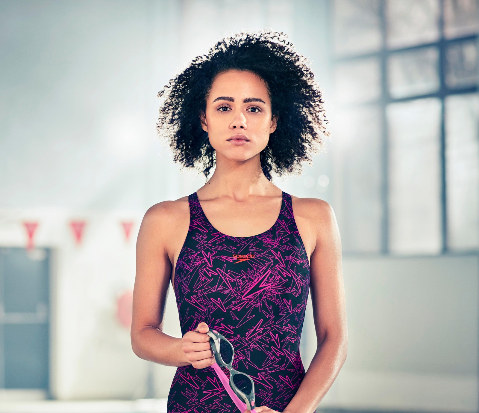 Une femme arabe en top violet tenant une raquette de tennis. (nathalie emmanuel, 5k, actrice britannique, hollywood, maillot de bain)