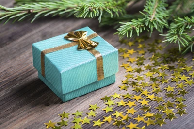 Turquoise Gift Box with Gold Ribbon Surrounded by Pine and Star Confetti