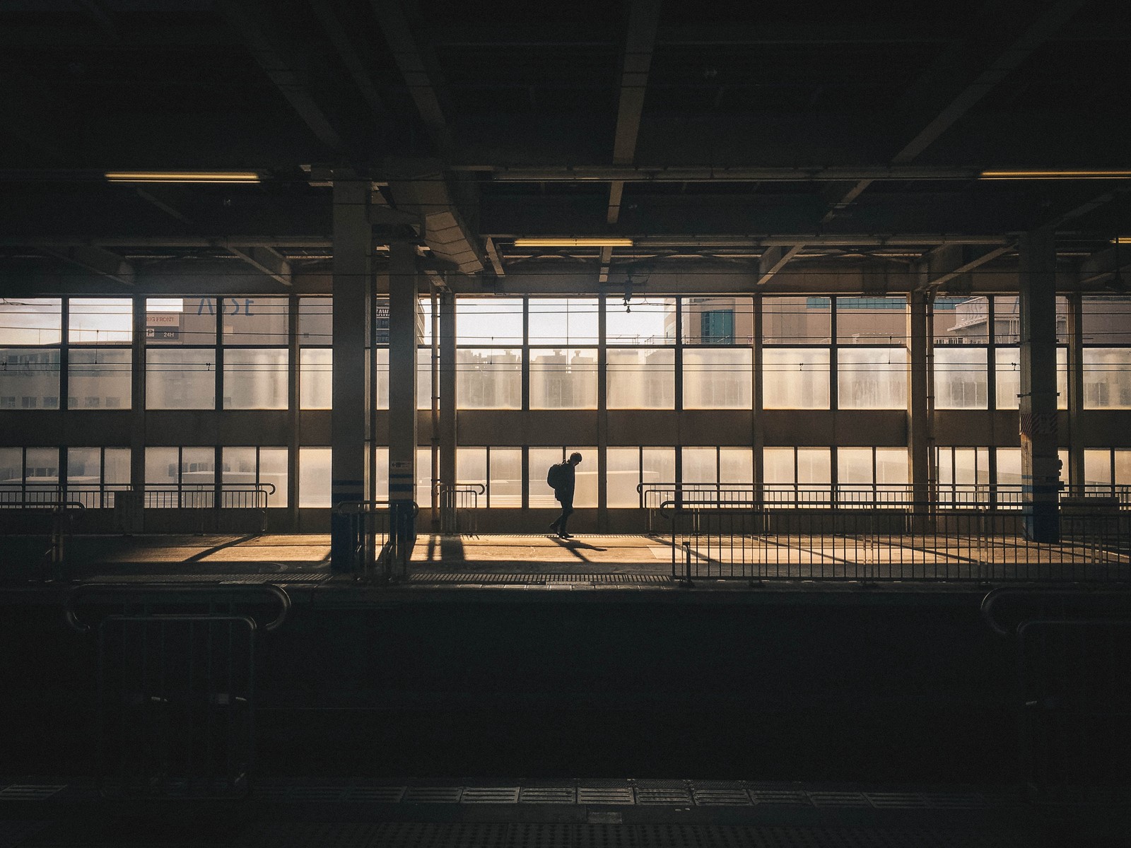 Hay una persona de pie en una habitación oscura con una patineta. (hierro, japón, línea, edificio, metal)