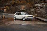 Klassischer Volkswagen Golf parkt an einer malerischen Straße mit rauen Felsen im Hintergrund.