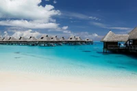 Bungalows sobre a água em Bora Bora, cercados por águas de lagoa turquesa e um céu vibrante.