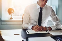 Empresário em traje formal escrevendo na mesa do escritório