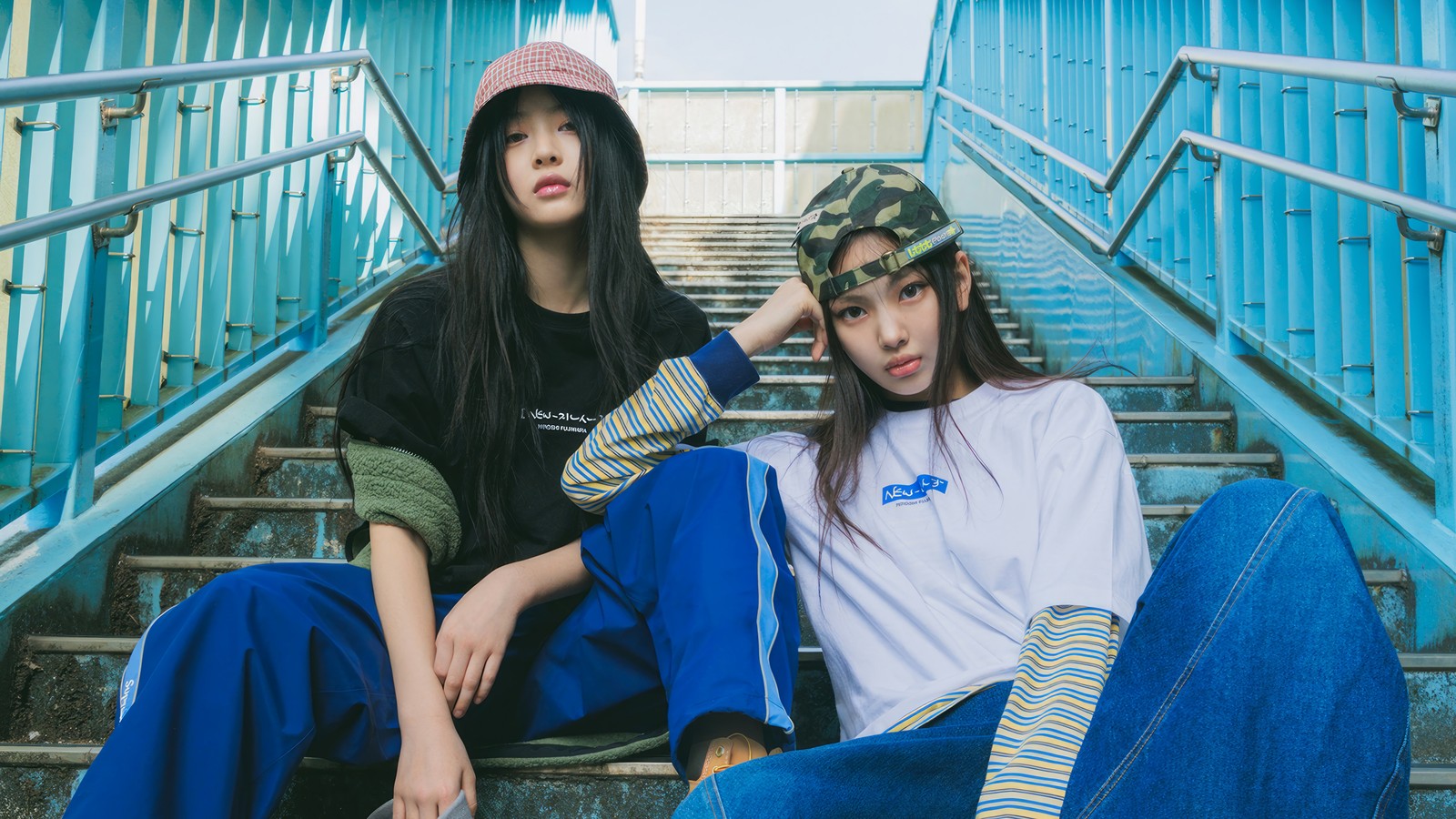 Two women sitting on stairs wearing hats and blue jeans (hanni, hyein, newjeans, kpop, new jeans)