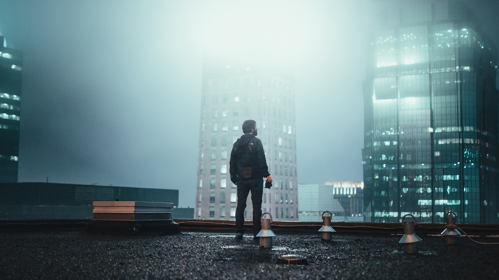 Un homme arabe debout sur un toit au milieu d'une ville la nuit (debout, eau, journée, atmosphère, pluie)