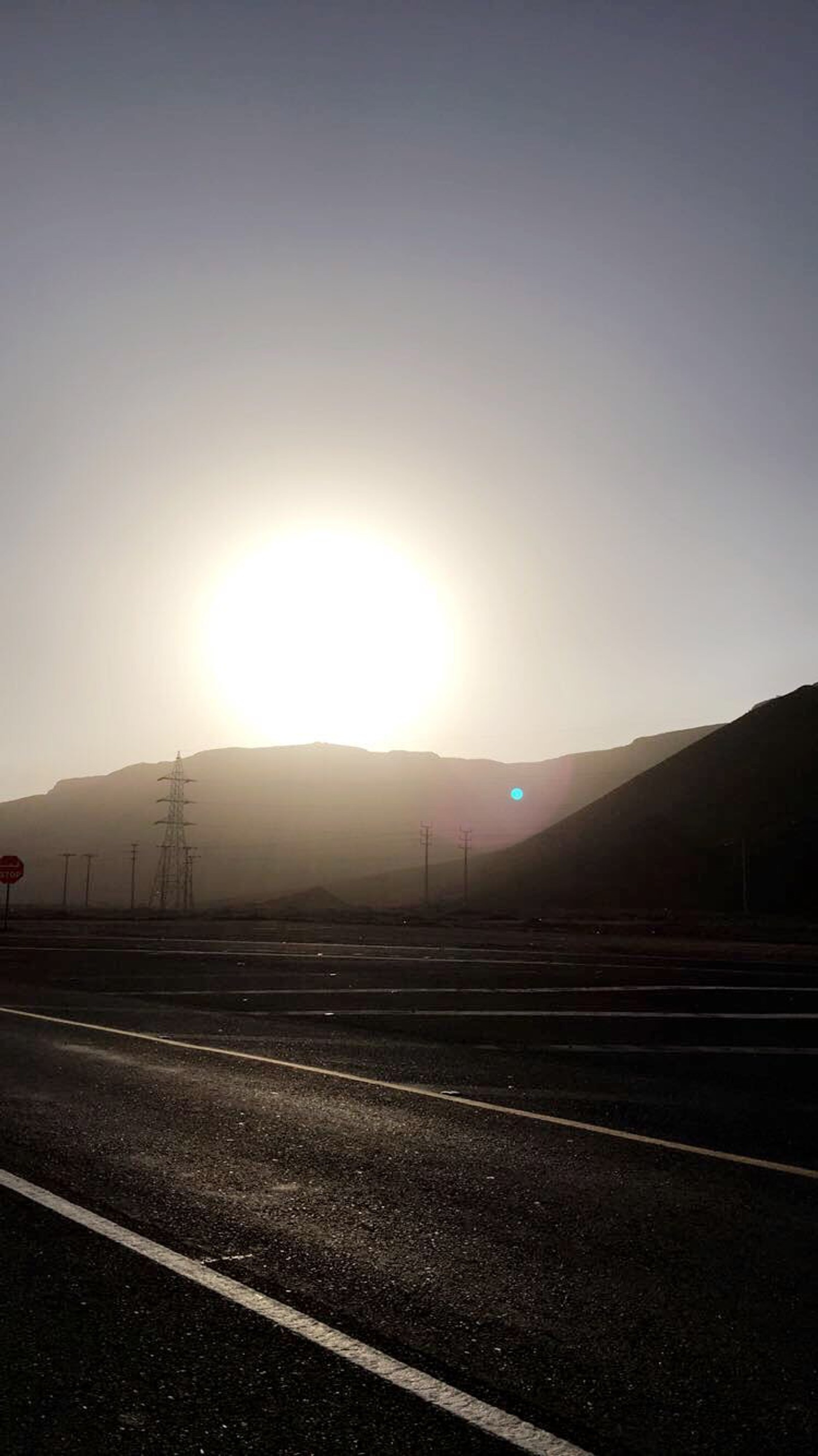 Vista aérea de una carretera con una señal de alto y montañas al fondo (barcelona nature movies, desierto, perros del sol)