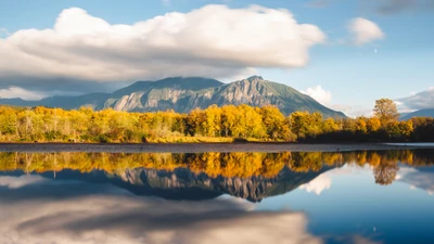 Serenidad Otoñal: Lago Reflectante Rodeado de Montañas y Árboles Dorados