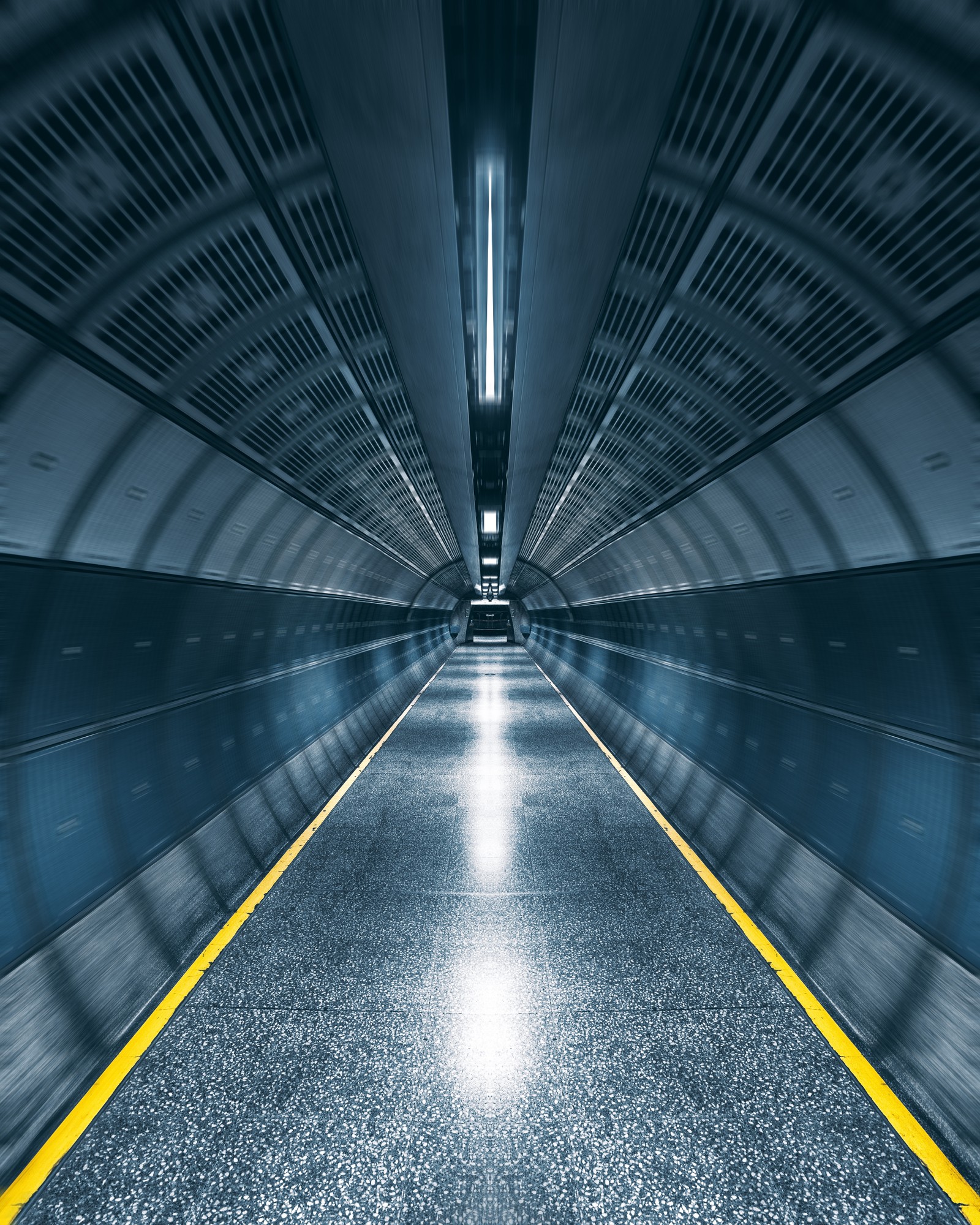 There is a long tunnel with a yellow line going through it (light, symmetry, line, architecture, infrastructure)