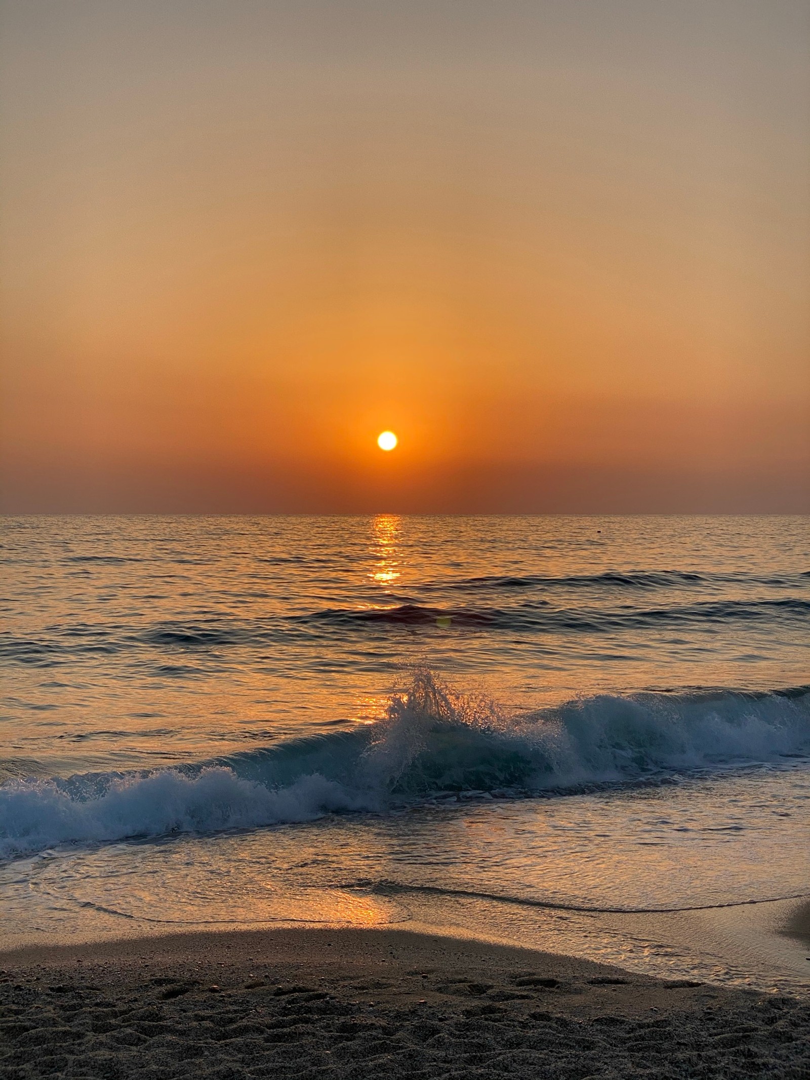 Pôr do sol sobre o oceano com um surfista caminhando na praia (mar, praia, apartamento, acomodação, férias)