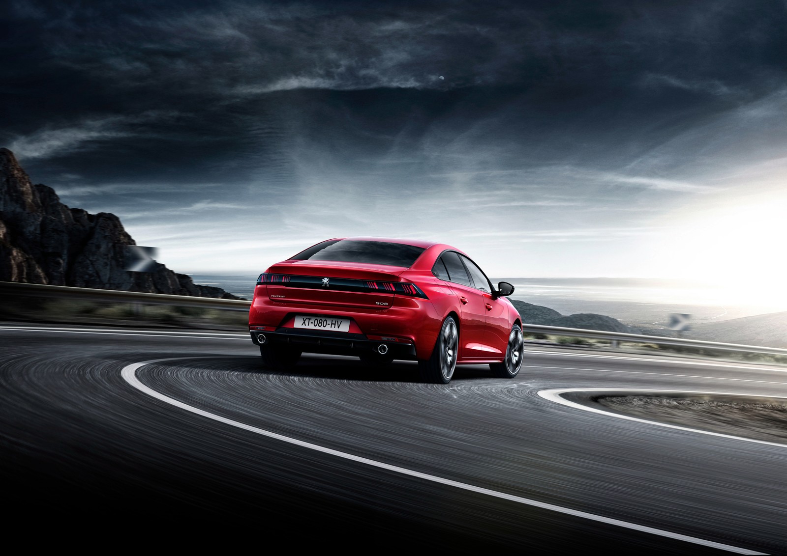 A red car driving down a winding road under a cloudy sky (peugeot, sports car, executive car, mid size car, sedan)