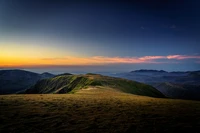 Paisaje montañoso sereno al anochecer con vibrante resplandor del atardecer