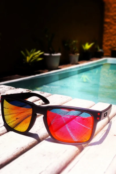 Sunglasses Reflecting Vibrant Colors by a Tranquil Poolside