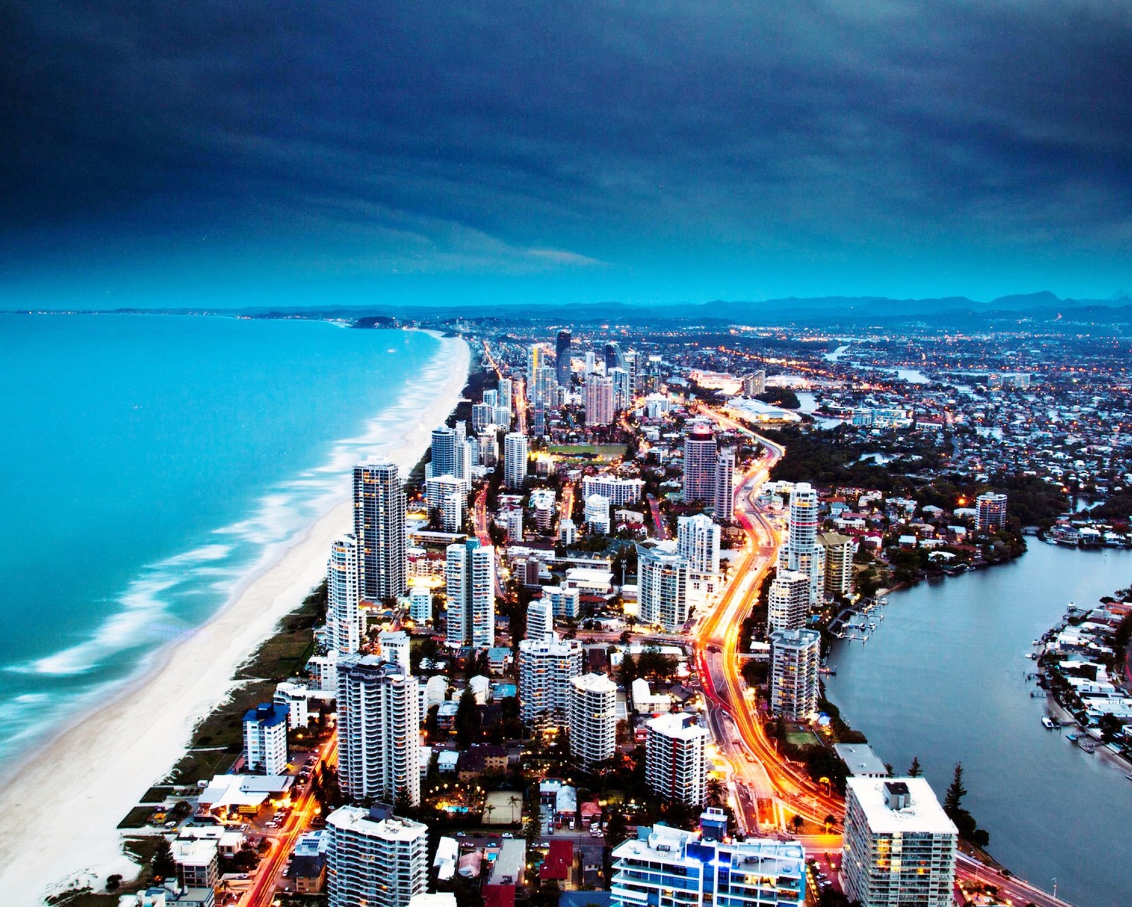 Arafed view of a city with a beach and a body of water (buildings, cityscape, coast, gold, landscape)