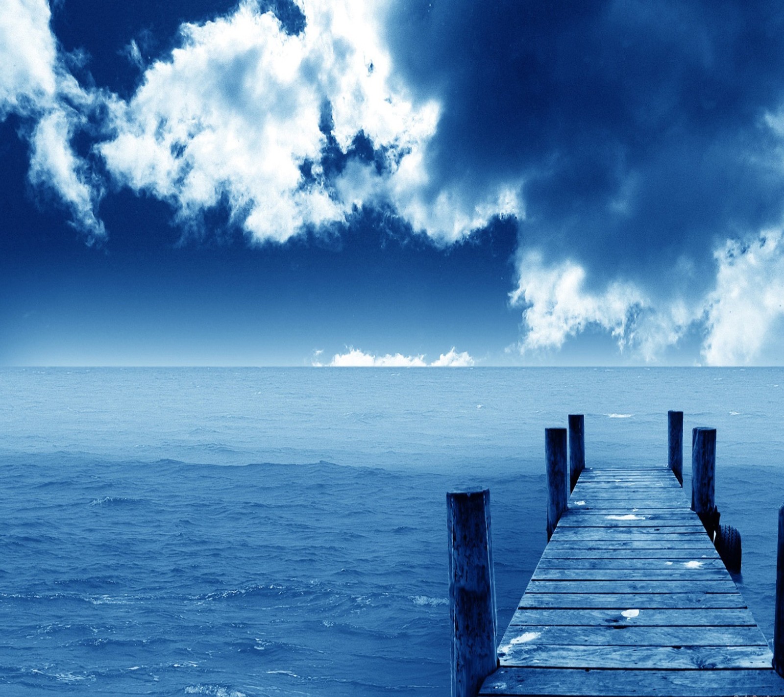 Vista aérea de un muelle en medio del océano con un cielo nublado (paisaje, fondo de pantalla)