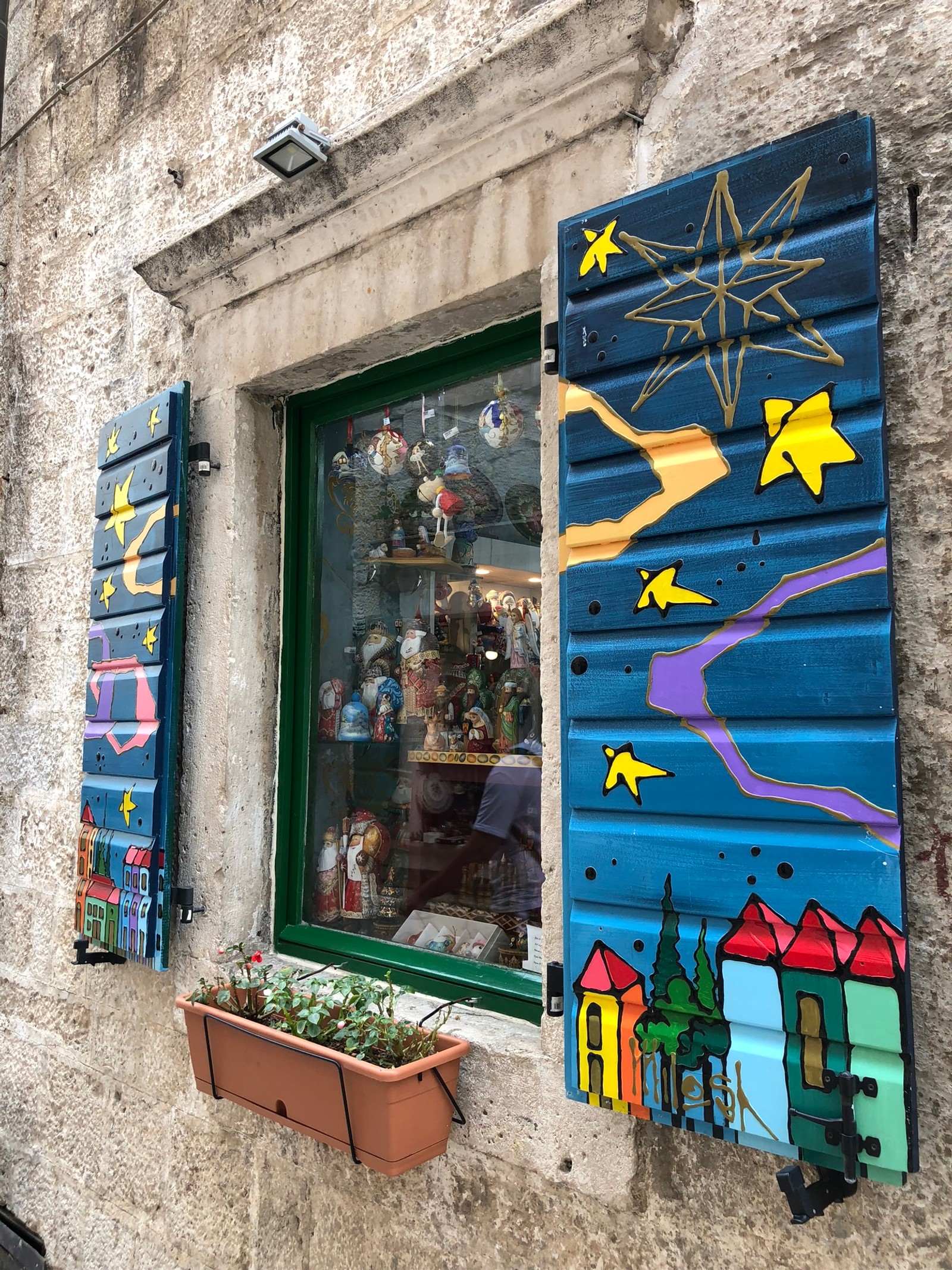 There is a window with a painting on it and a flower pot (wall, street art, flowerpot, majorelle blue, houseplant)