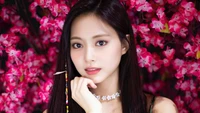 Tzuyu de TWICE entourée de fleurs roses vibrantes, incarnant l'élégance et le charme.