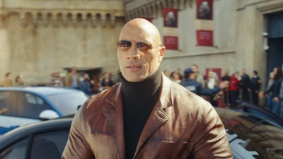 Dwayne Johnson con una chaqueta de cuero marrón en medio de una escena bulliciosa en "Red Notice" (2021).