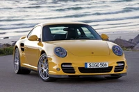 Porsche 911 Turbo amarillo estacionado junto a la playa, mostrando su diseño elegante y características de rendimiento.