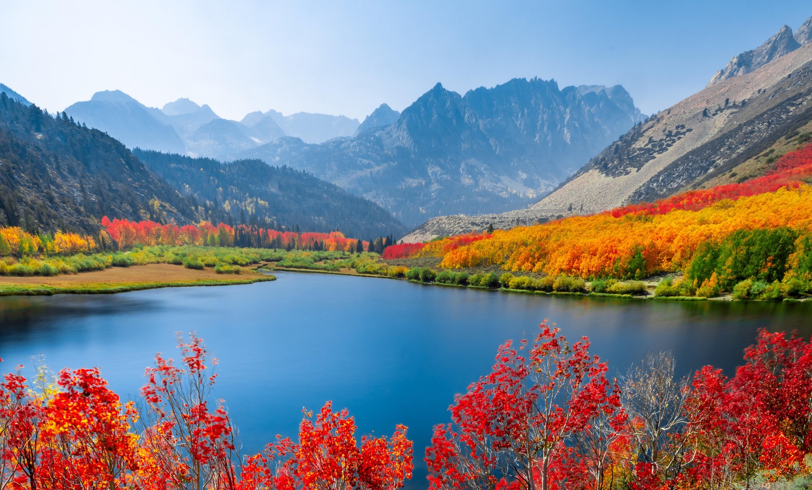 A lake surrounded by colorful trees in the mountains (autumn trees, lake, mountain range, daytime, landscape)