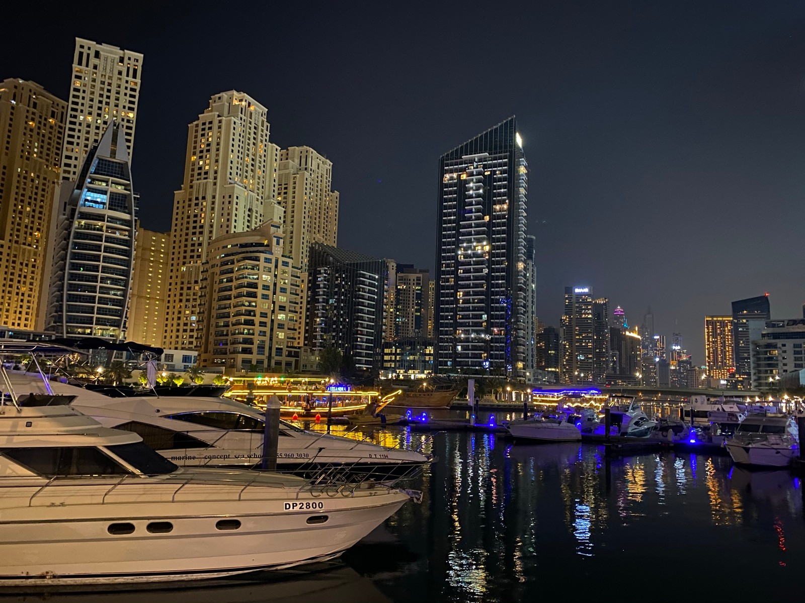 Лодки пришвартованы у воды перед горизонтом города (дубай, dubai, дубайская марина, городской пейзаж, башенный блок)